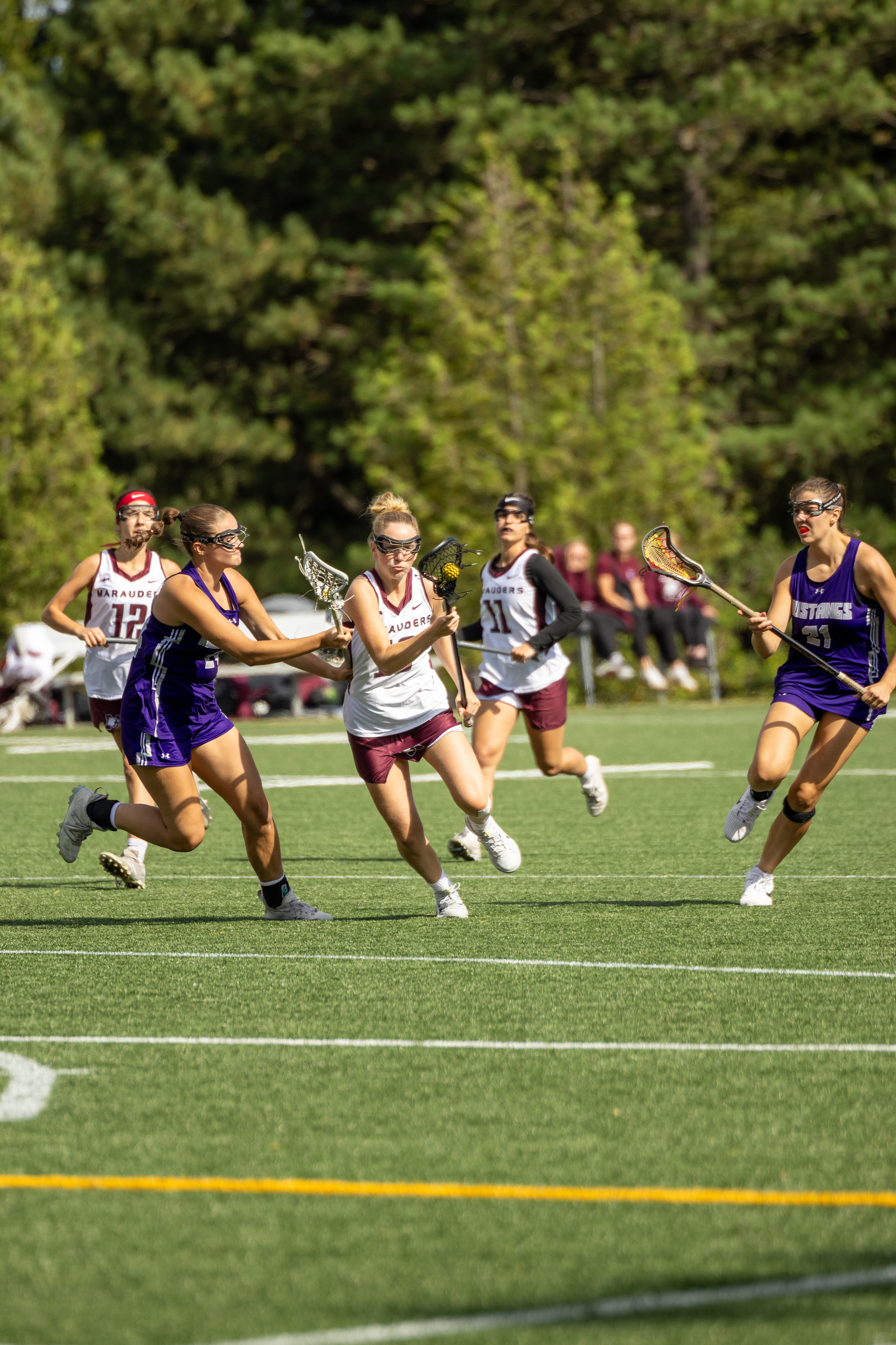 Female lacrosse players sprinting during an outdoor game in York Region